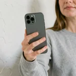 Femme tenant un iPhone 12 dans la main pour illustrer sa taille réelle