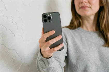 Femme tenant un iPhone 12 dans la main pour illustrer sa taille réelle