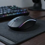 Souris gaming sans fil sur tapis de souris avec clavier mécanique en arrière-plan dans un setup gaming sombre